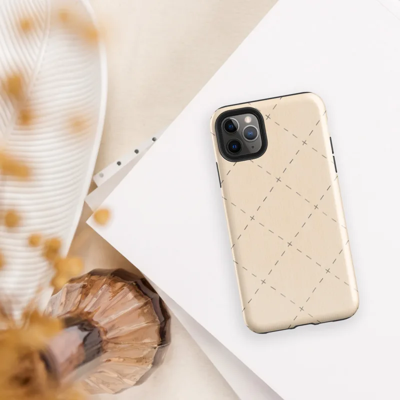 repeating diamond trellis of dashed lines and small cross stitches in soft grey on a warm blush cream background on Glossy Stitched Diamond Trellis Tough Case for iPhone - default view