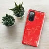 Glossy Crimson Storm Scratch Tough Case for Samsung — vivid red-orange background covered in scattered gray paint splatters